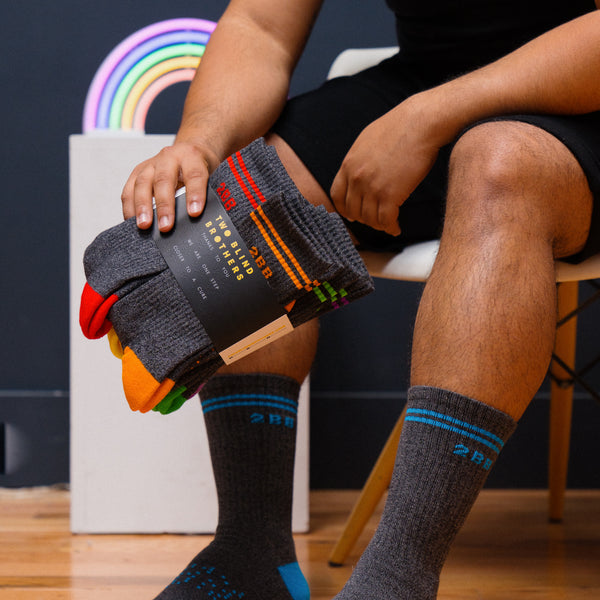 Two Blind Brothers - Gift Rainbow Calf Sock Bundle (6 Pairs) Model-wearing-blue-calf-socks-holding-six-pack-of-calf-socks