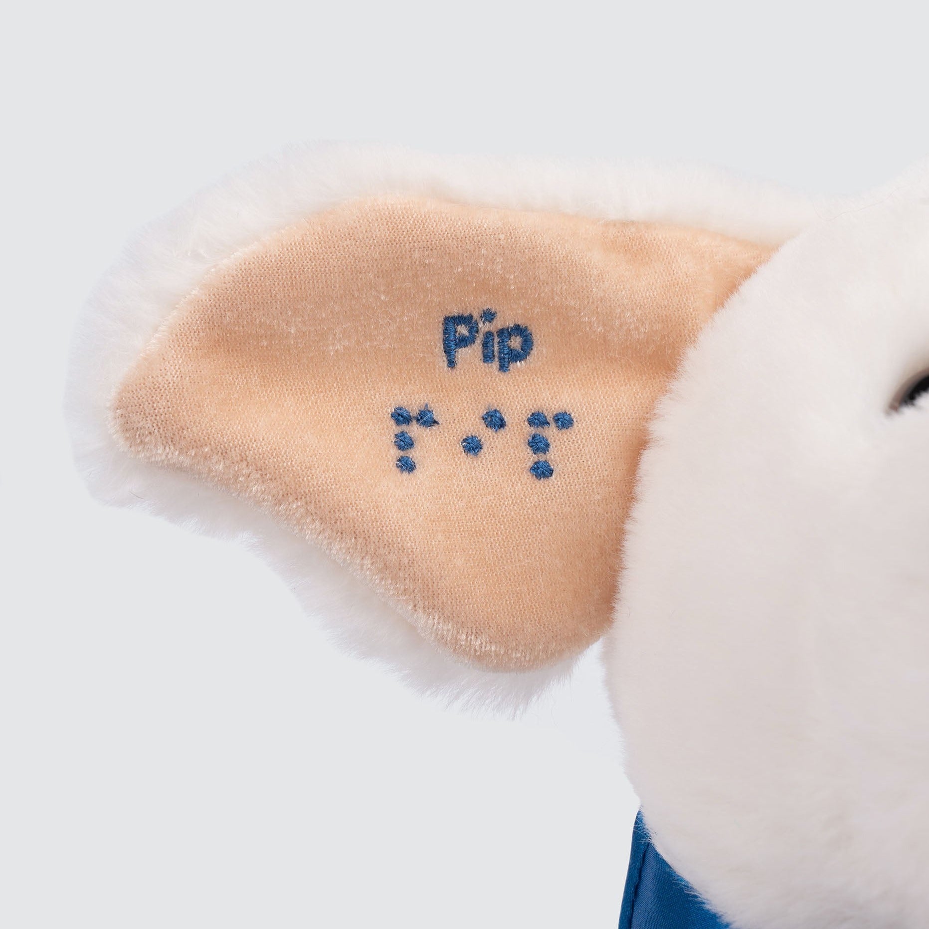 Two Blind Brothers - PIP AND FRIENDS PIP Pip-the-Guide-Dog-front-facing-view.-White-Labrador-plush-with-a-blue-cape-that-reads-"Pip"-and-"Pip"-written-in-text-and-braille-on-the-ear.